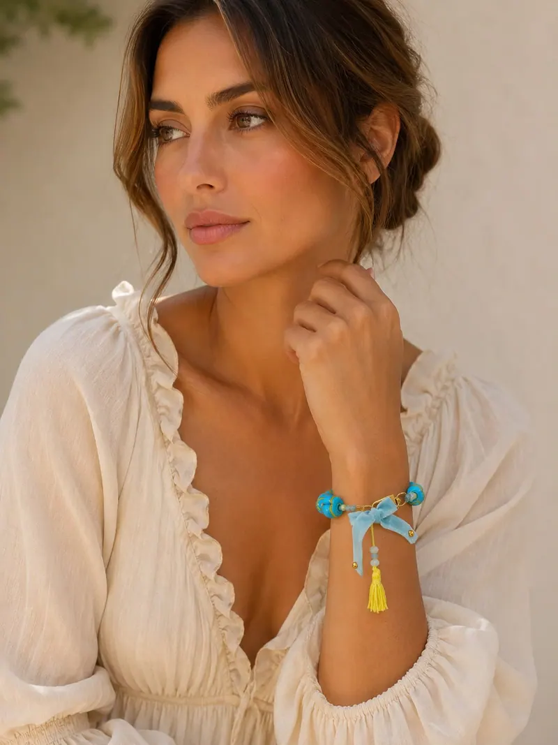 Modelo de blusa branca com pulseira de contas turquesa, laço azul e borla amarela