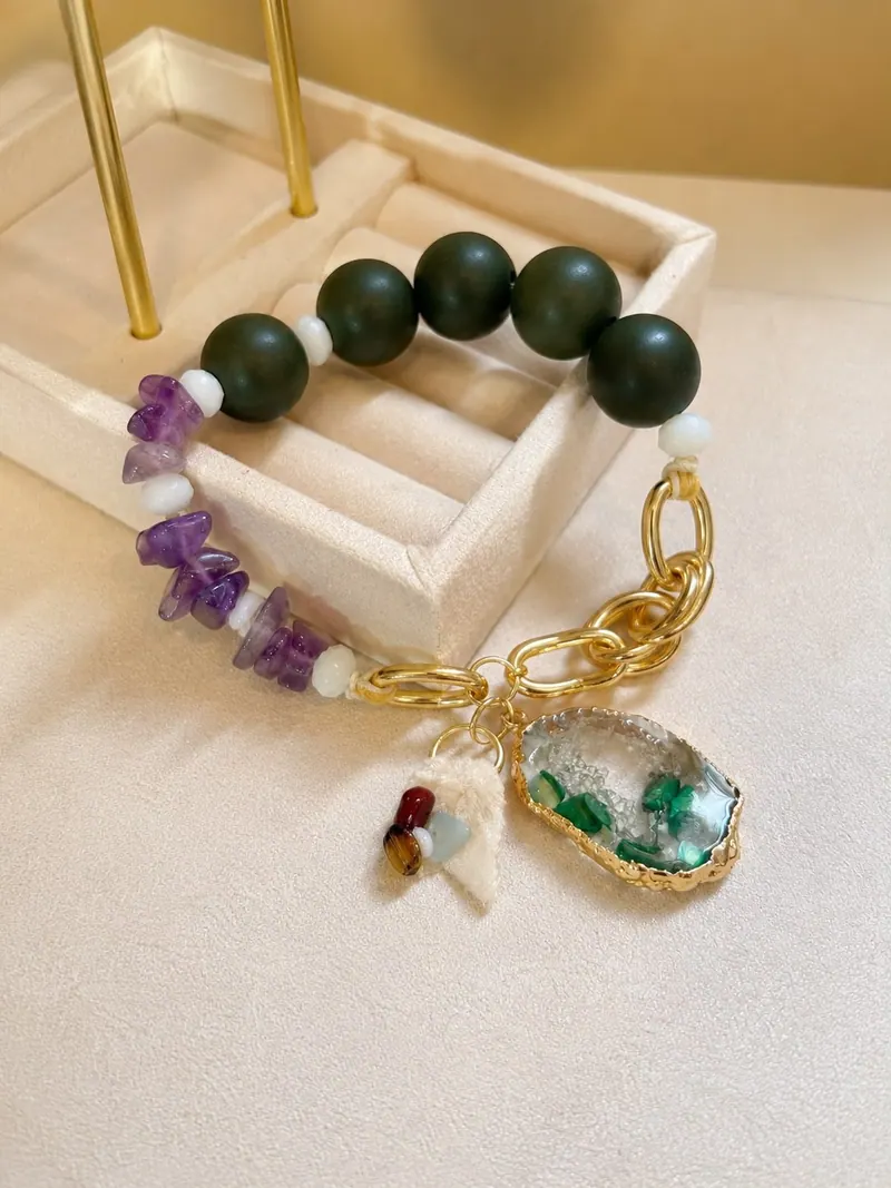Pulseira de bolas verde-escuras, quartzo lilás e apatitas brancas, com elos dourados e pingente de vidro